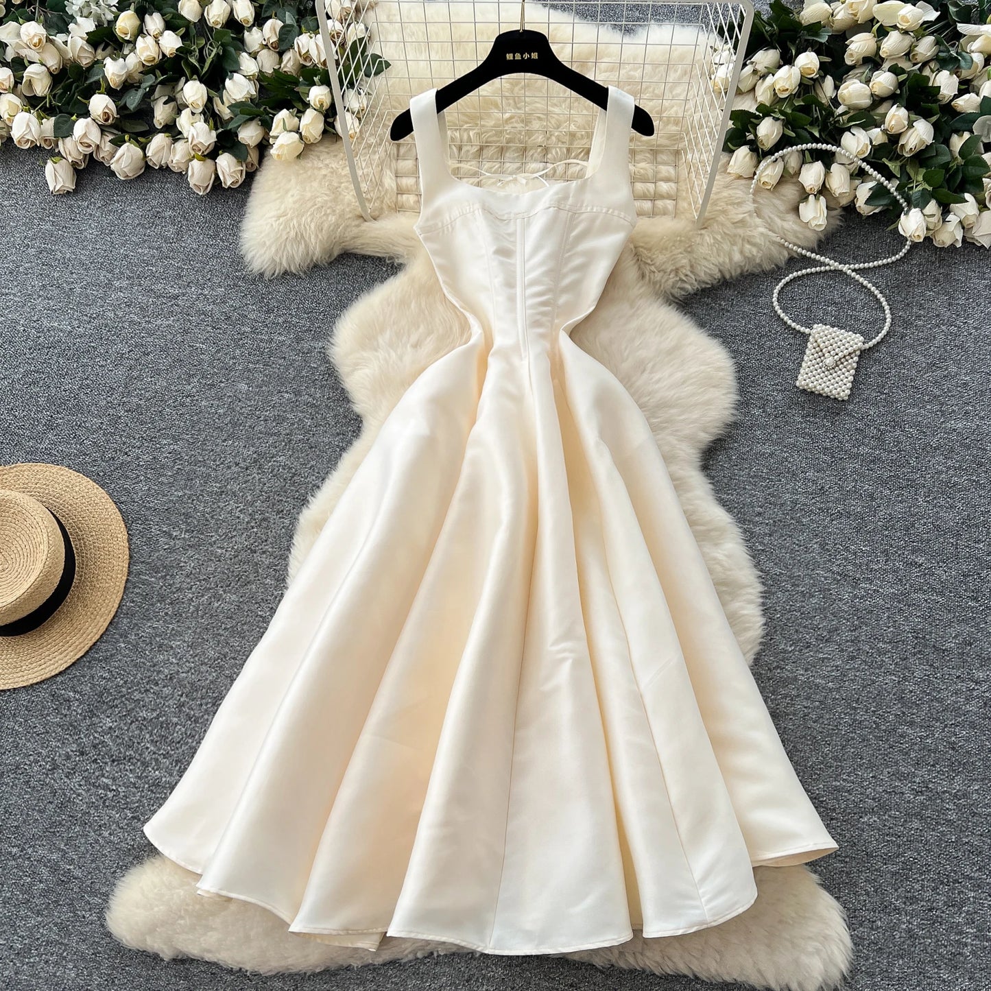 White dress on a hanger with decorative elements on a gray surface