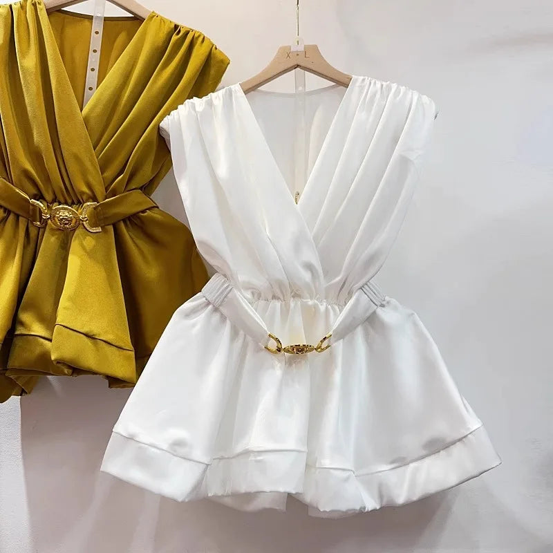 Yellow and white dresses with gold belts on hangers against a white background