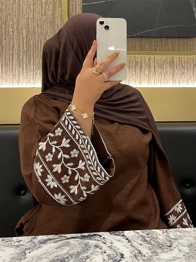 Person wearing a brown hijab and holding a phone with a marble background