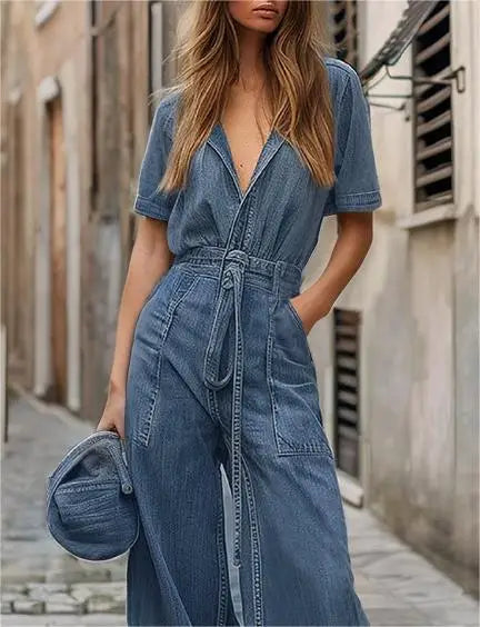 Woman wearing a blue denim jumpsuit walking down a street.
