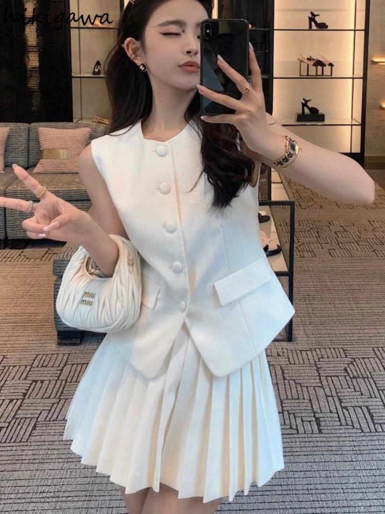 Woman taking a mirror selfie wearing a white outfit with a blurred background