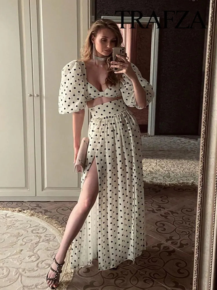 Woman in a polka dot dress taking a mirror selfie in a stylish interior setting.