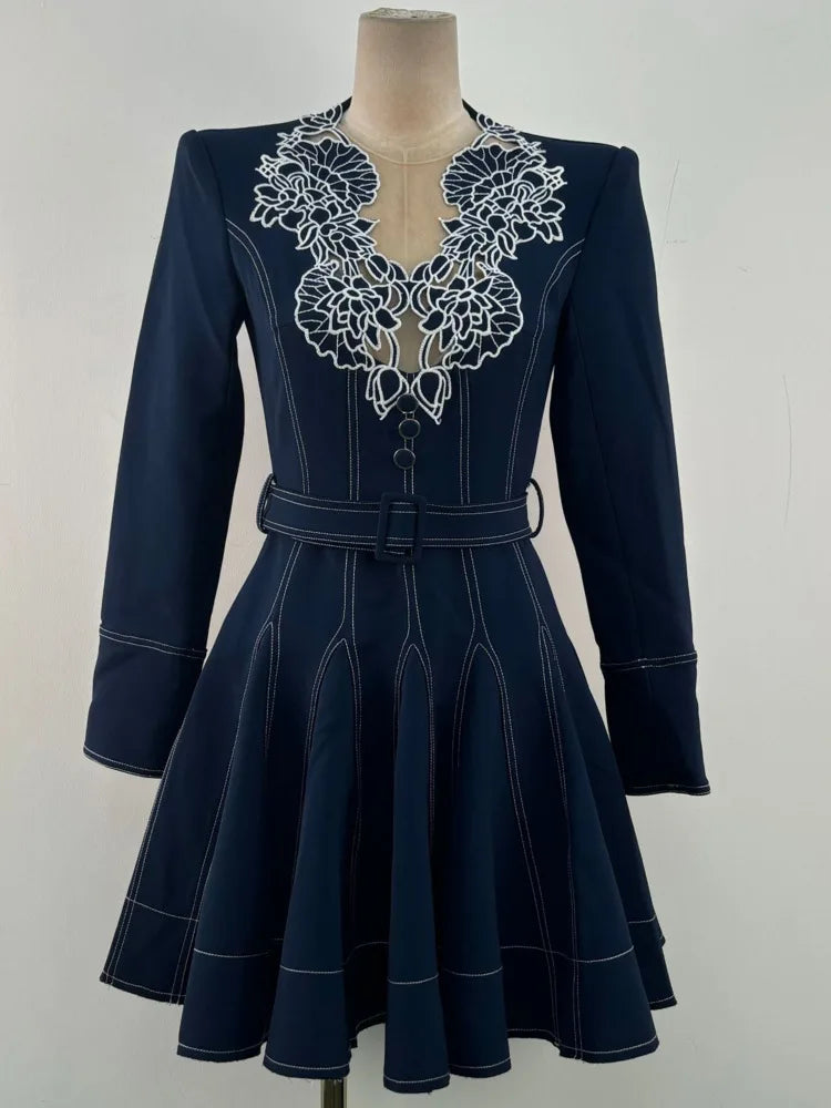 Navy blue dress with white lace detailing on a mannequin against a white background