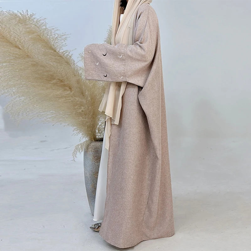 Person wearing a long beige coat with a neutral background