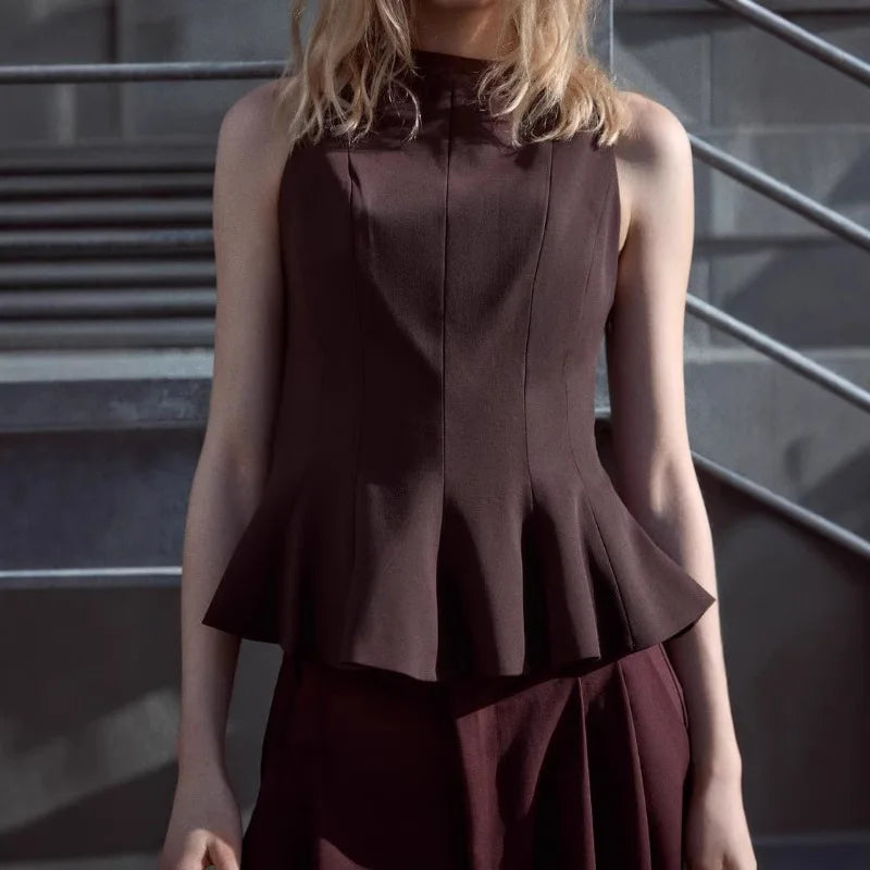Person wearing a brown peplum top against a neutral background