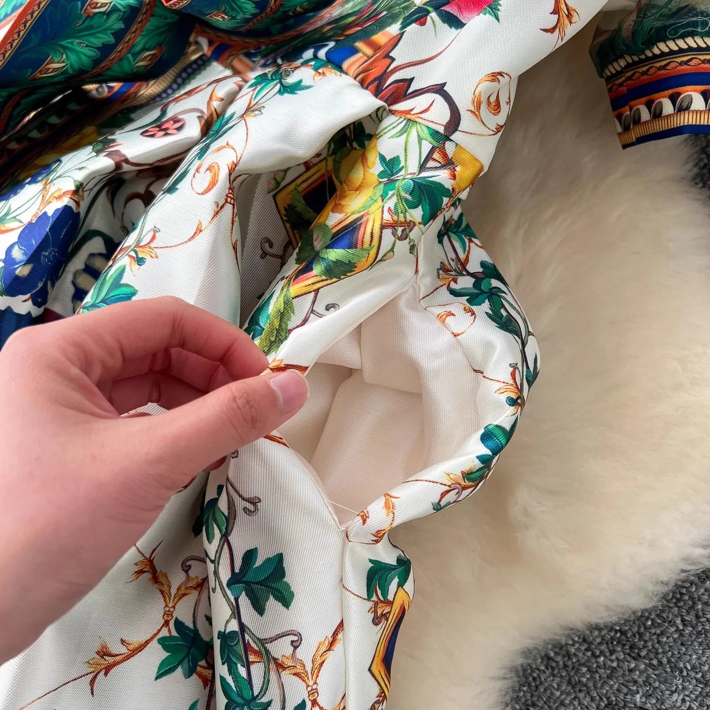 Close-up of a hand holding a piece of colorful fabric with floral patterns.