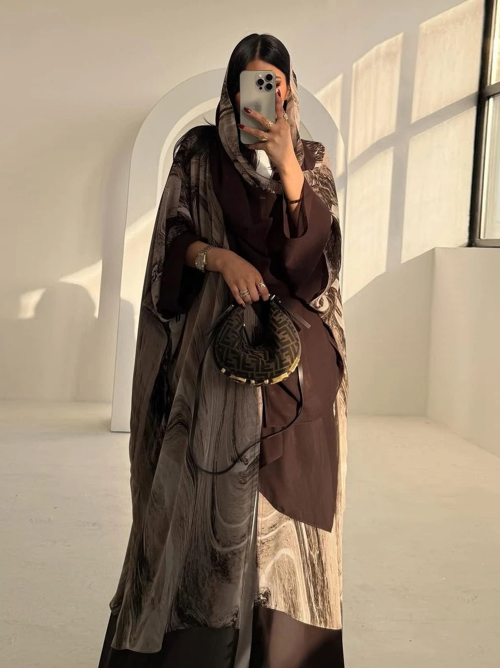 Person wearing a long, patterned coat in a softly lit room.