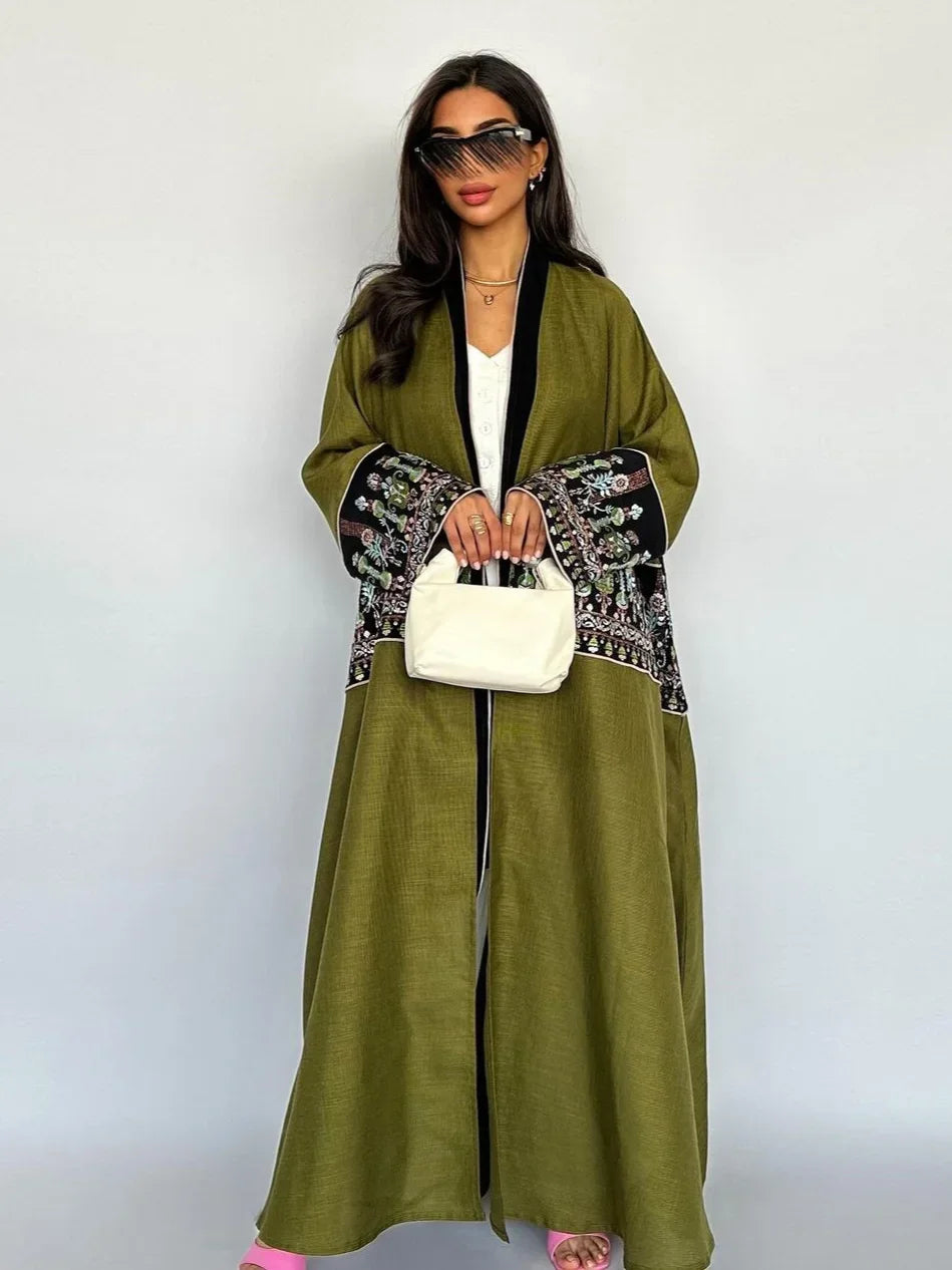 Woman wearing a green dress with black and white patterned sleeves against a white background