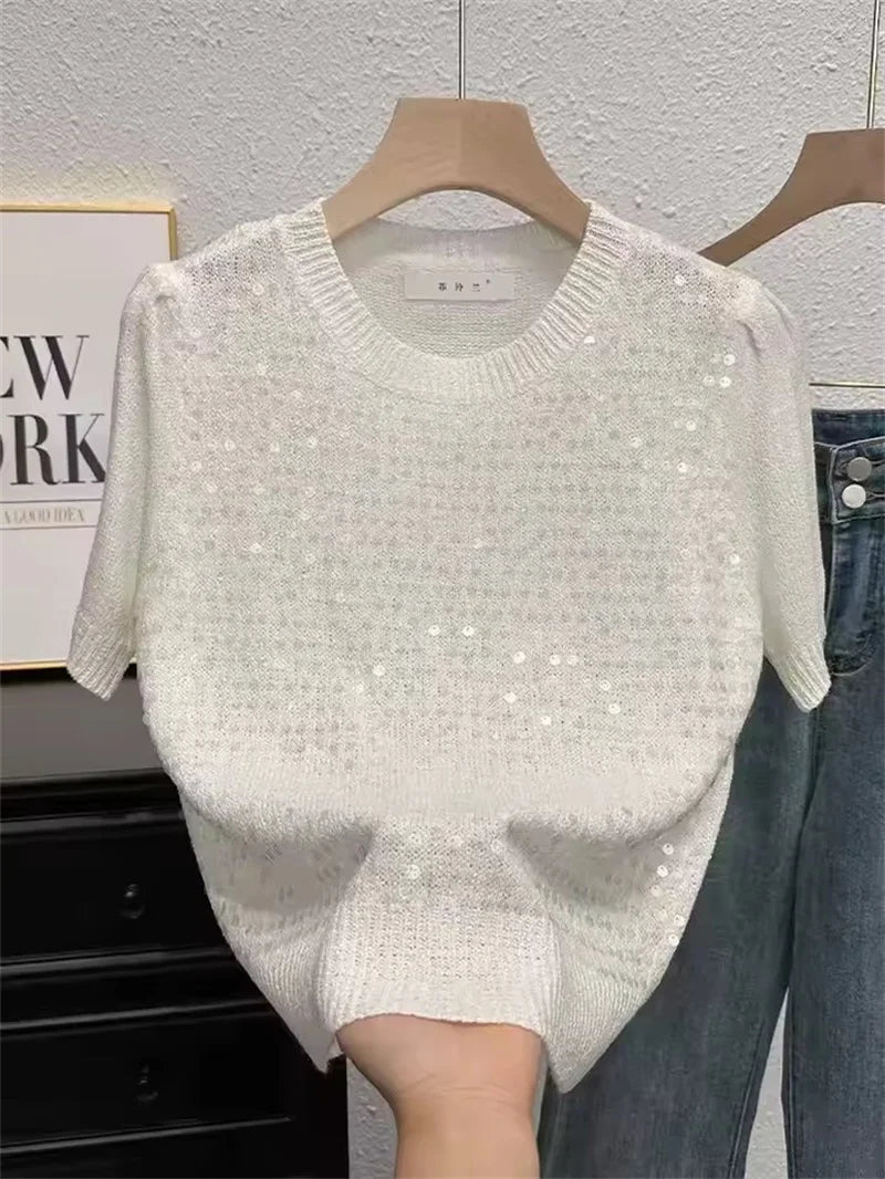 Silver sequin poncho on a hanger against a neutral background