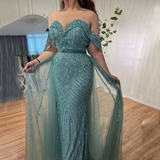 Teal beaded evening gown with sheer overlay in a room setting