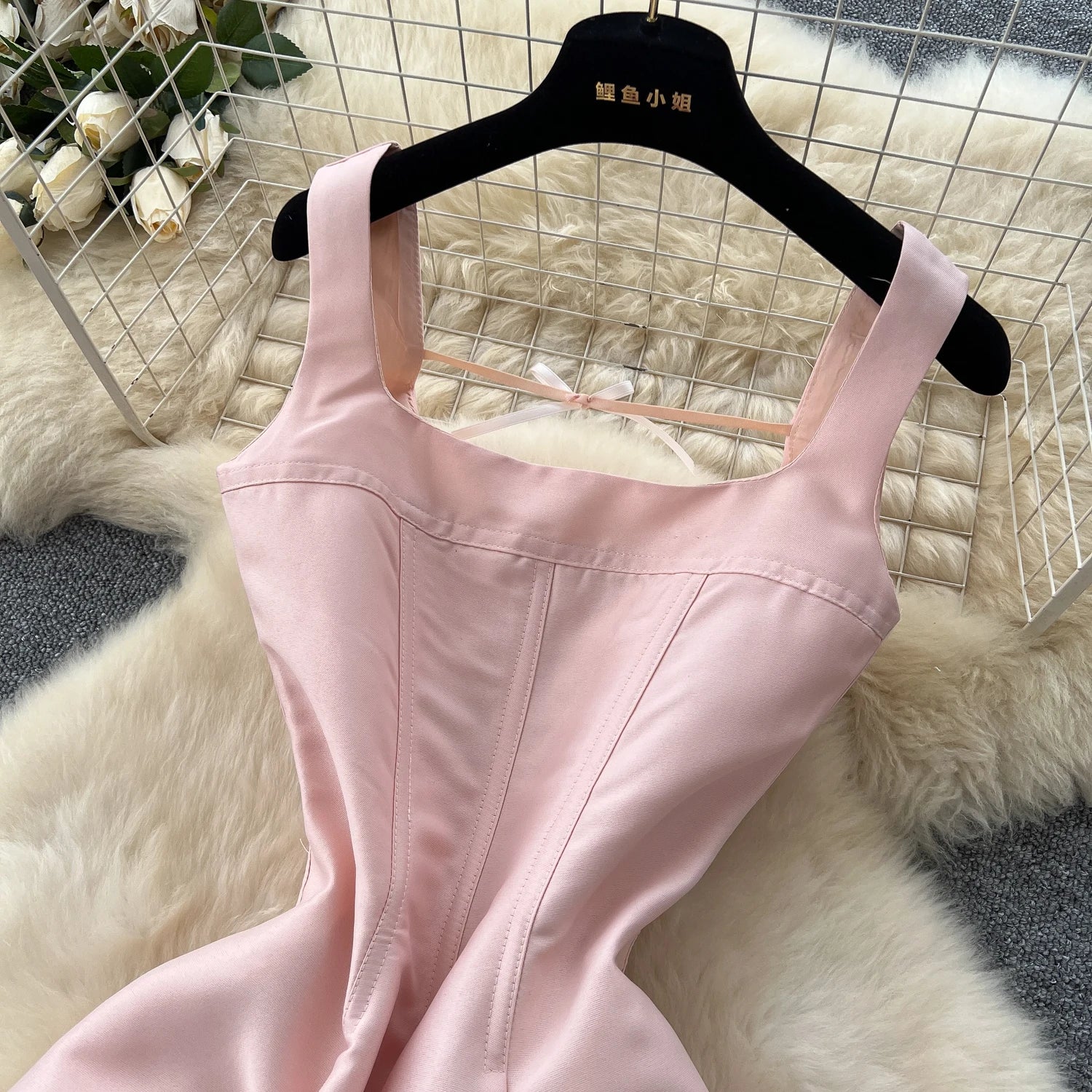 Pink dress on a hanger against a textured white background