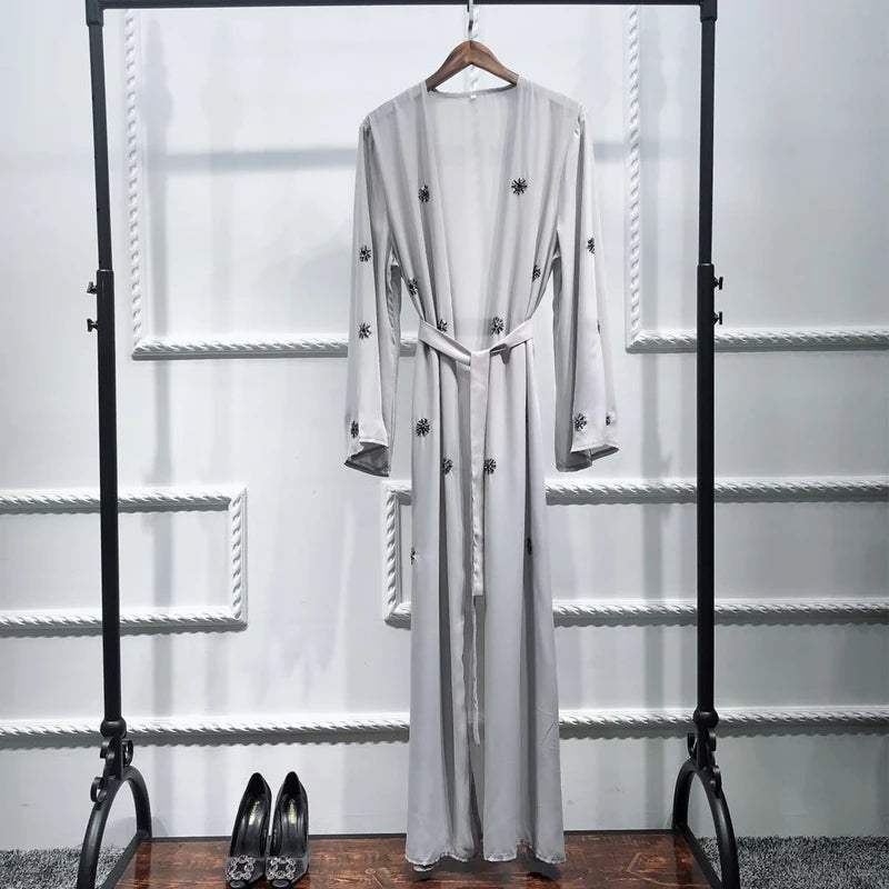 Long white dress with black buttons on a hanger against a white background