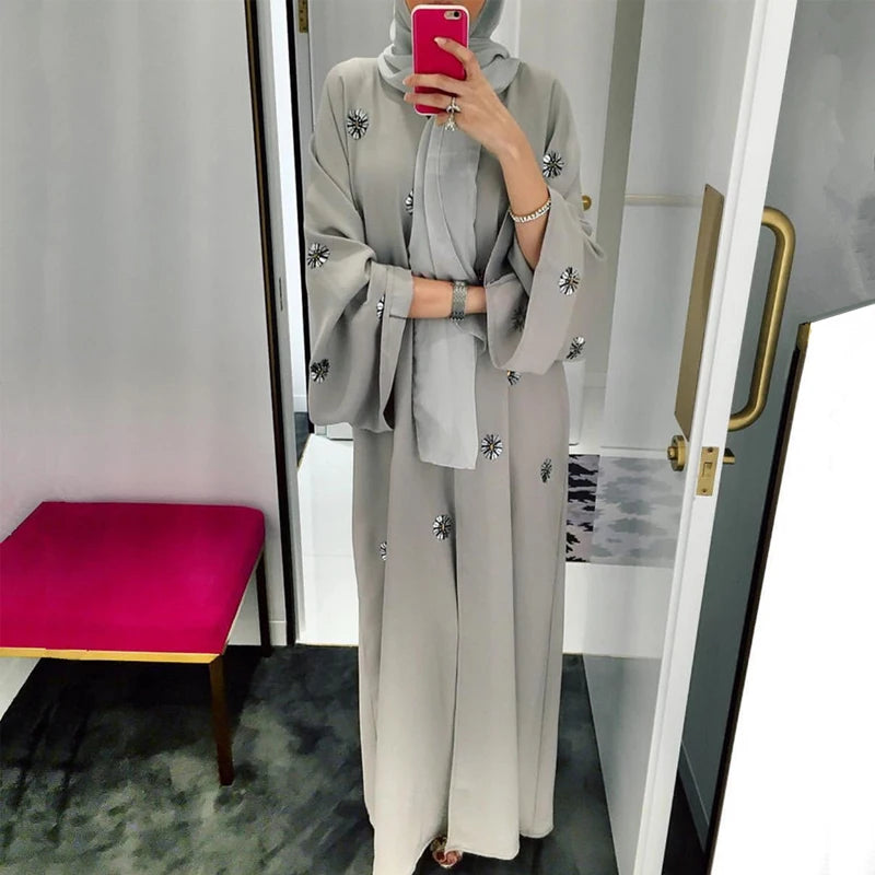 Person wearing a gray outfit with floral embellishments in front of a mirror.