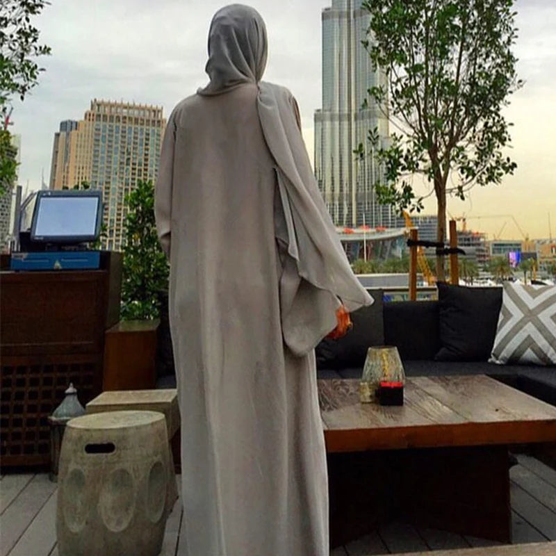 Person in a light-colored outfit standing on a rooftop with cityscape and trees in the background