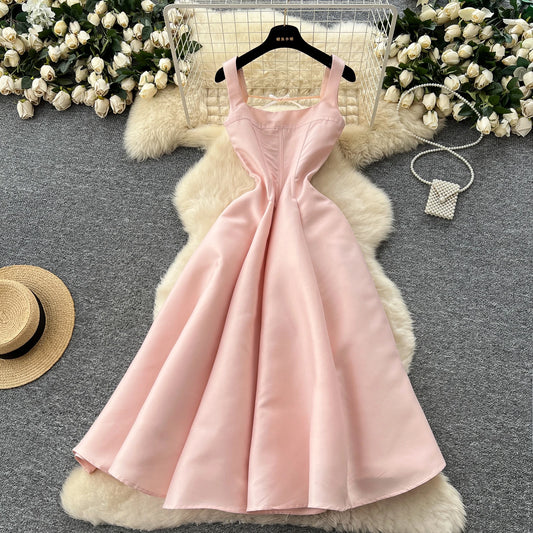 Pink dress on a hanger with decorative flowers and a hat in the background