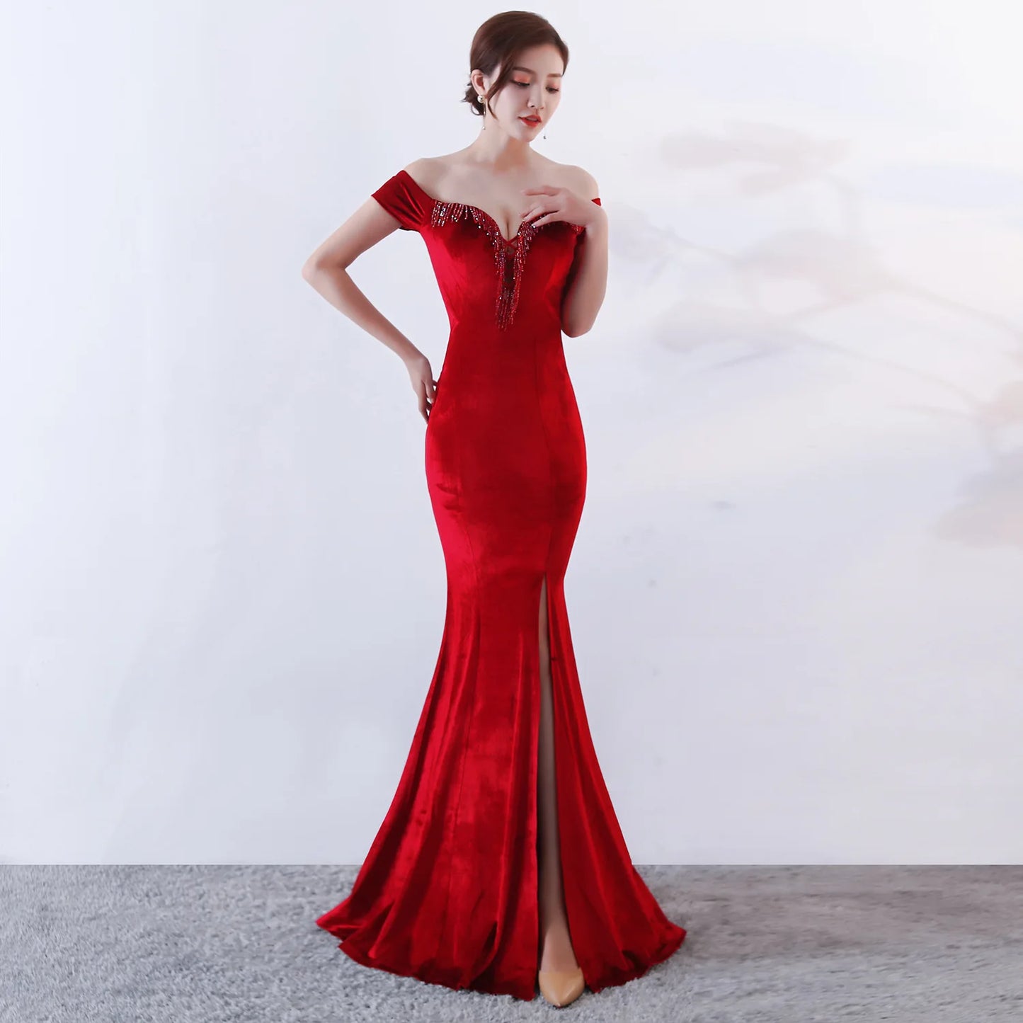 Woman wearing a red evening gown with a high slit on a white background