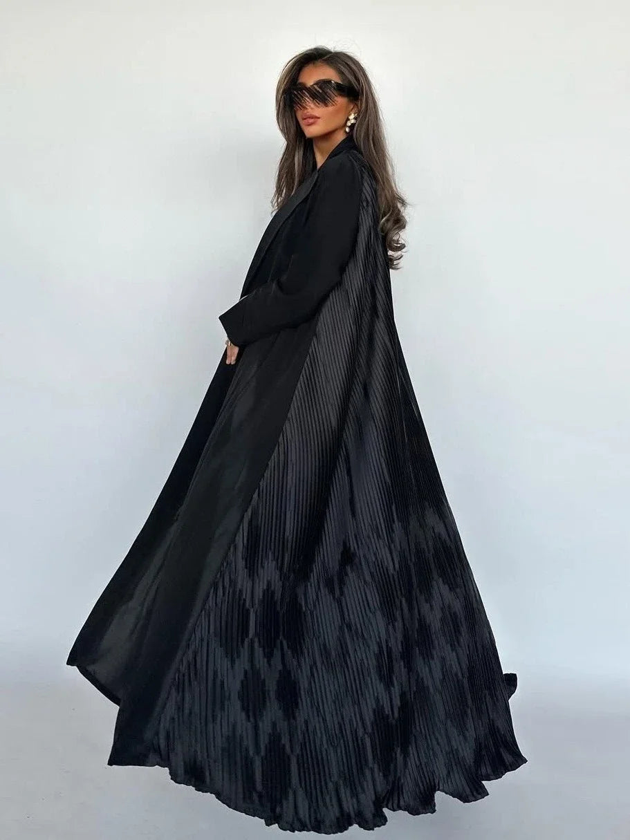 Woman wearing a long black dress with geometric patterns against a white background