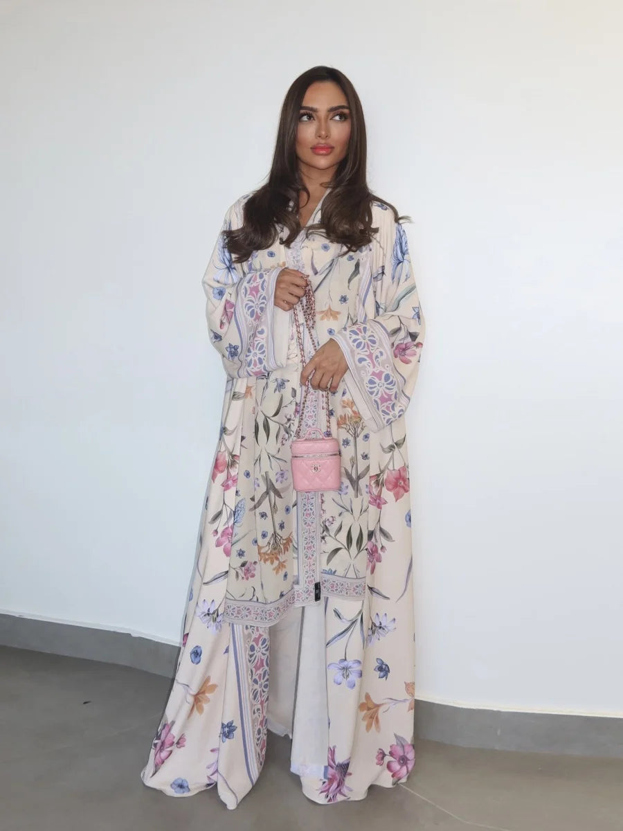 Woman wearing a floral dress holding a pink handbag against a white wall.