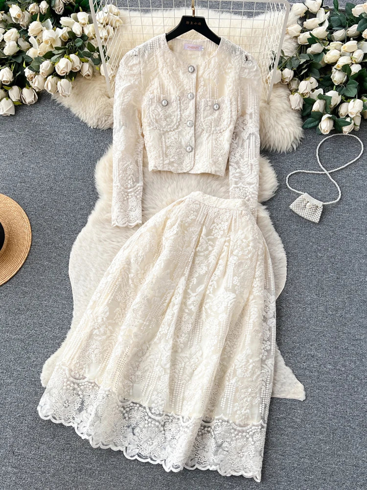White lace dress with matching jacket on a gray surface with decorative elements.