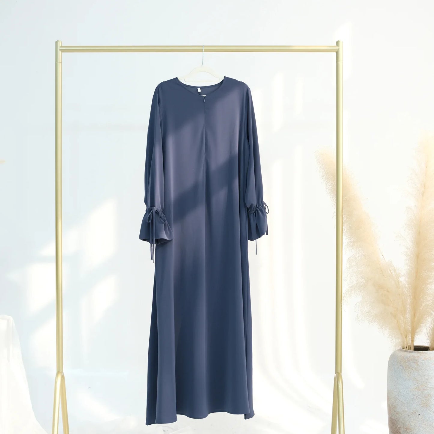 Navy blue dress hanging on a gold rack with a white background