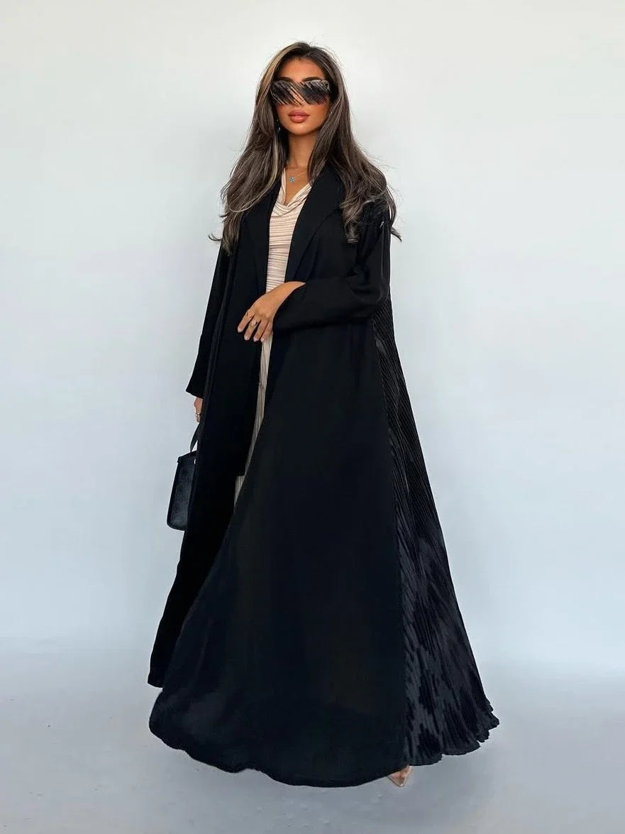 Woman wearing a long black coat against a white background