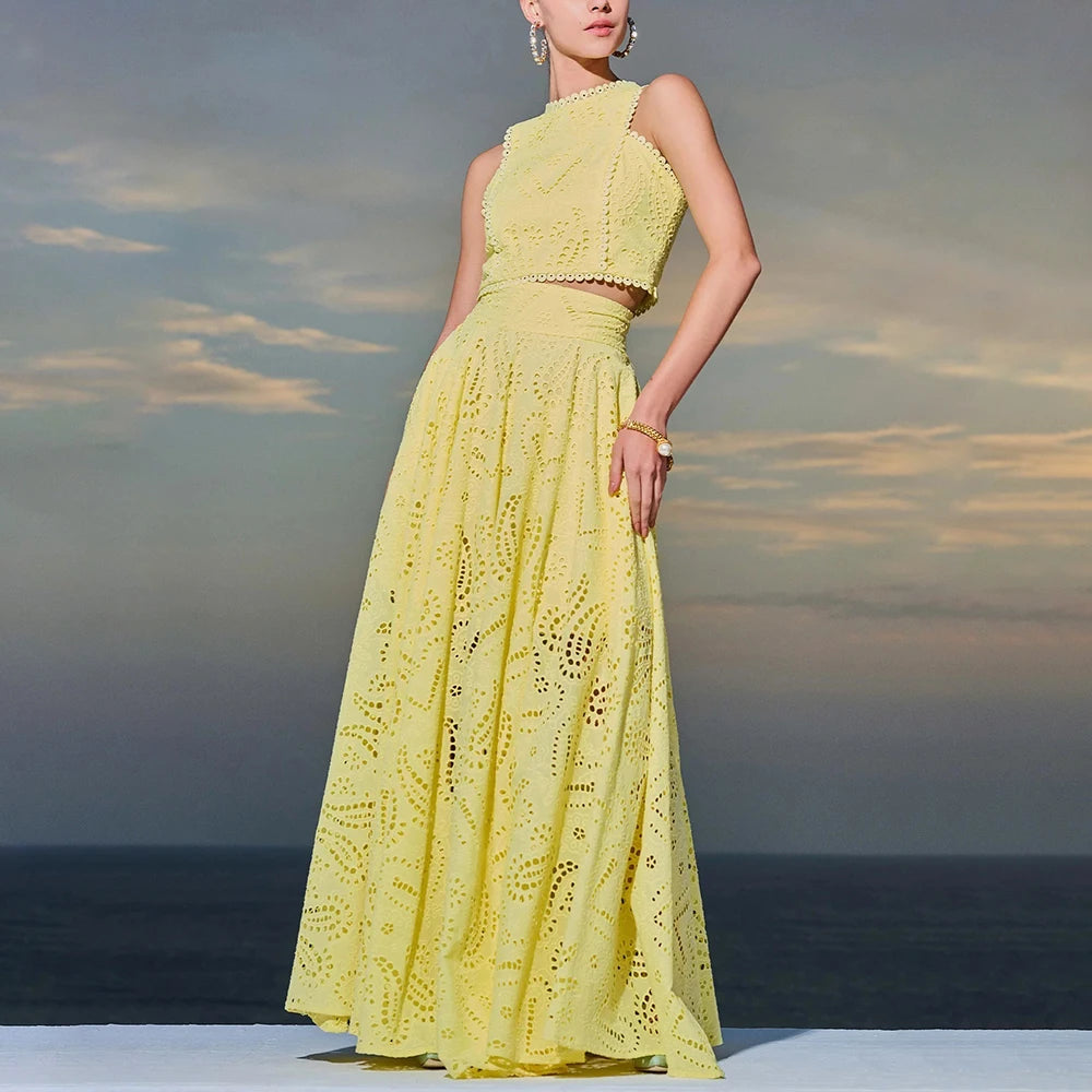 Woman in a yellow lace dress standing against a cloudy sky and ocean background