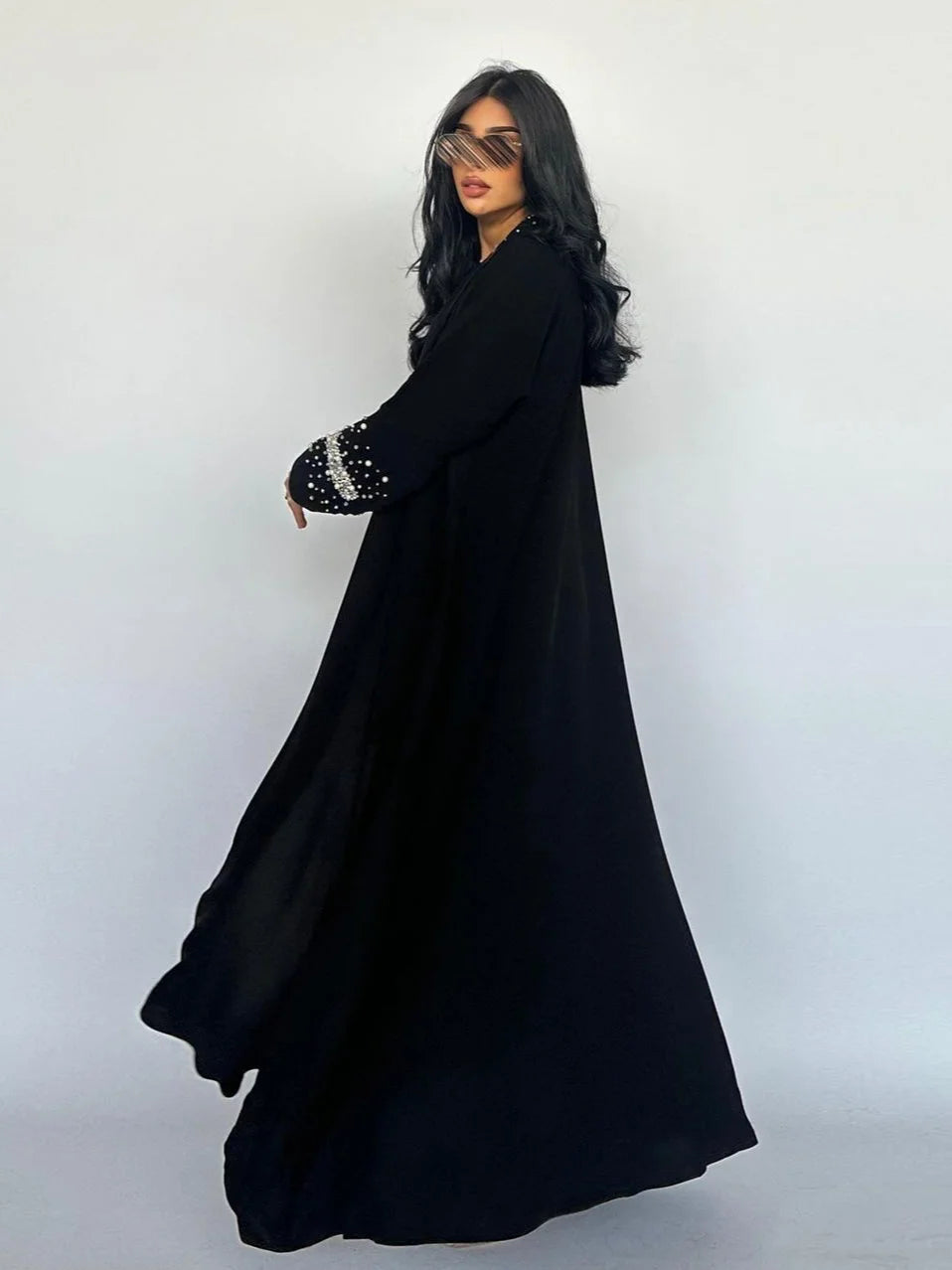 Woman wearing a black dress with embellished sleeves against a white background