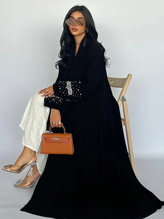 Woman in a black outfit with a brown handbag sitting on a chair against a white background