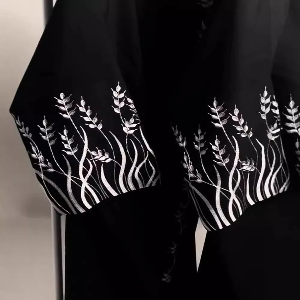 Black fabric with white floral embroidery on a neutral background