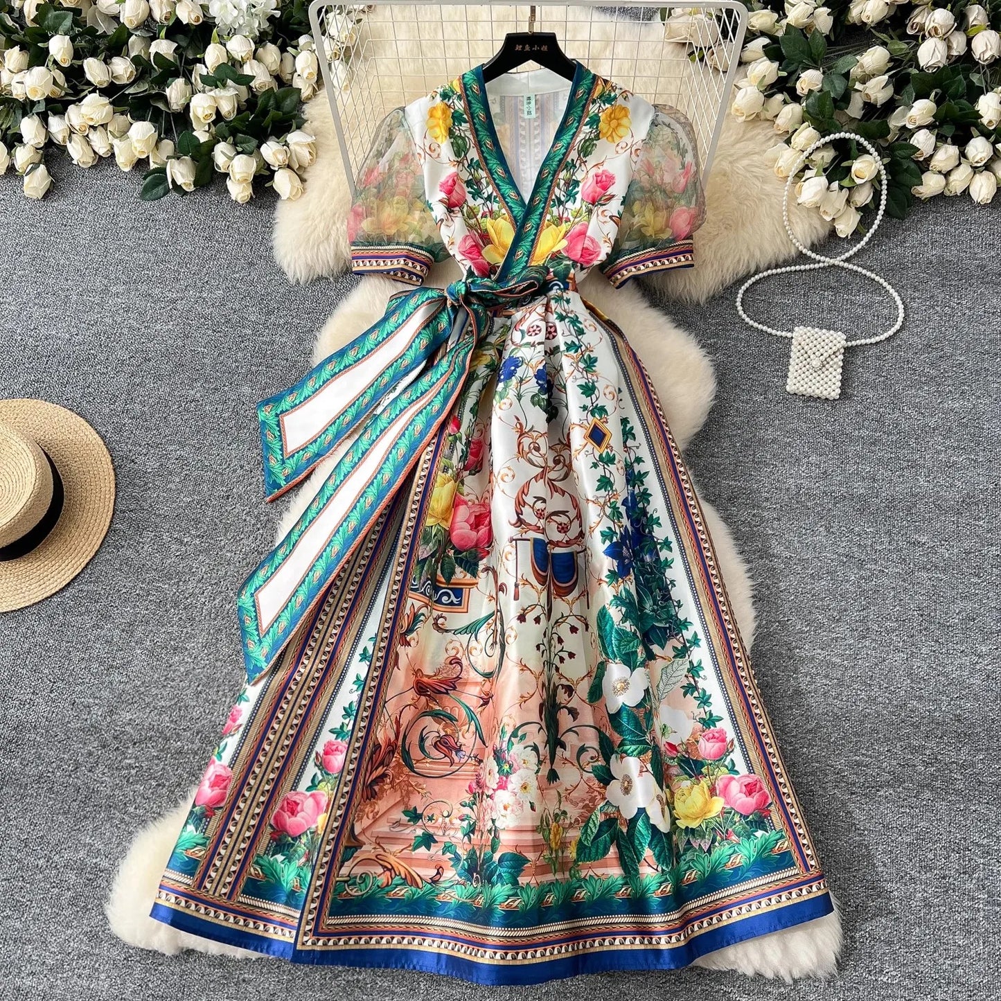 Colorful floral dress with a fur-lined coat on a gray surface with decorative elements.