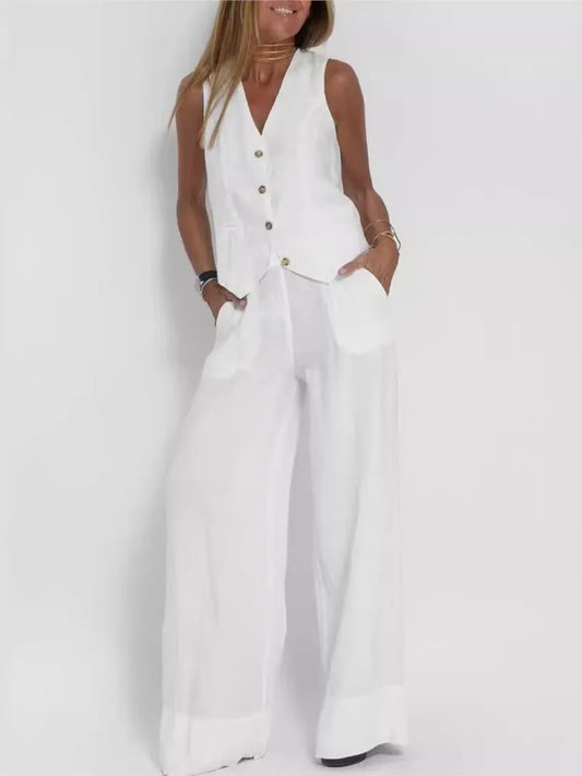 Woman wearing a white sleeveless top and wide-leg pants on a plain background