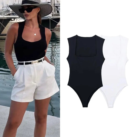 Woman in black tank top and white shorts with a black swimsuit on a white background