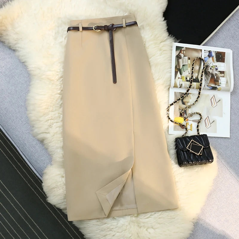 Beige skirt with a belt on a textured surface next to a magazine and handbag.