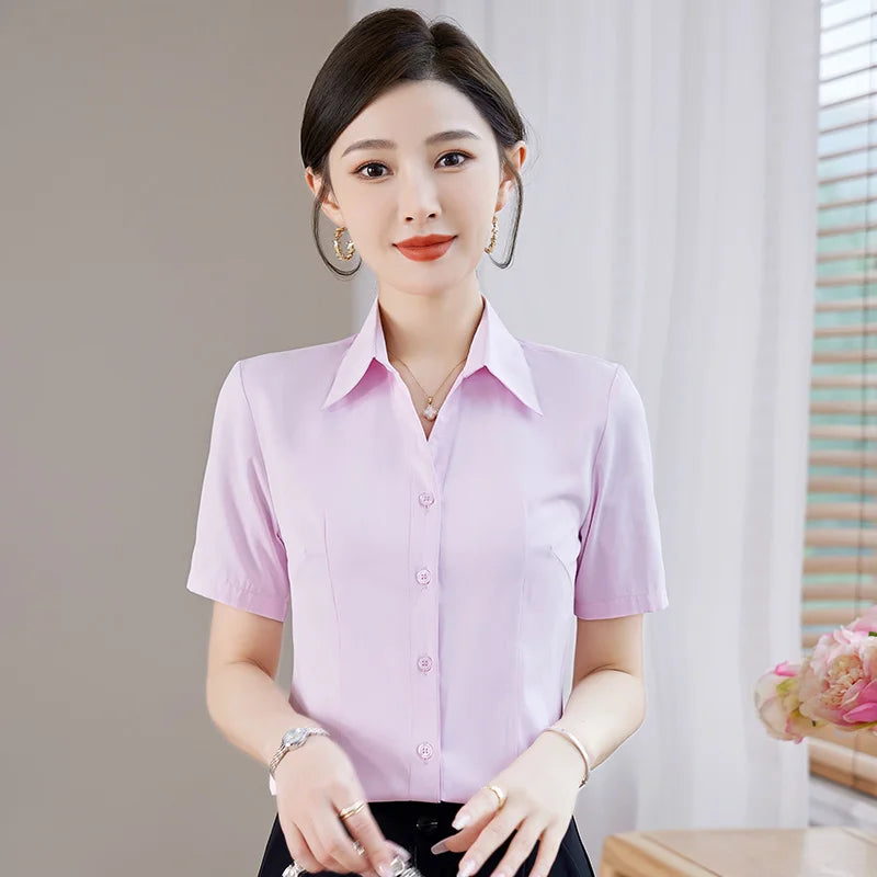 Woman wearing a light purple short-sleeve shirt indoors with a neutral background