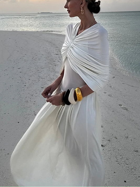 Woman in a white dress standing on a beach with 'ZAHM' branding.