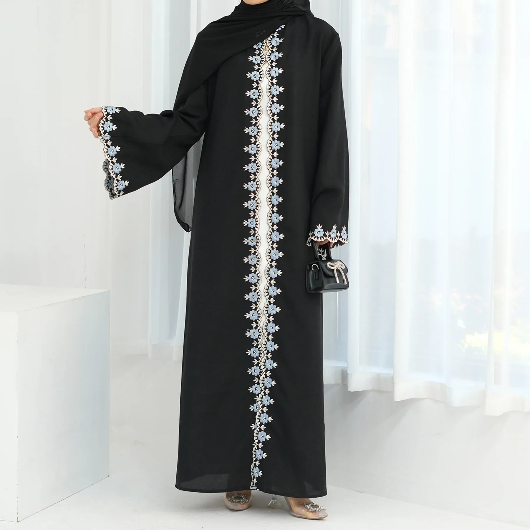 Black abaya with white embroidery on a white background