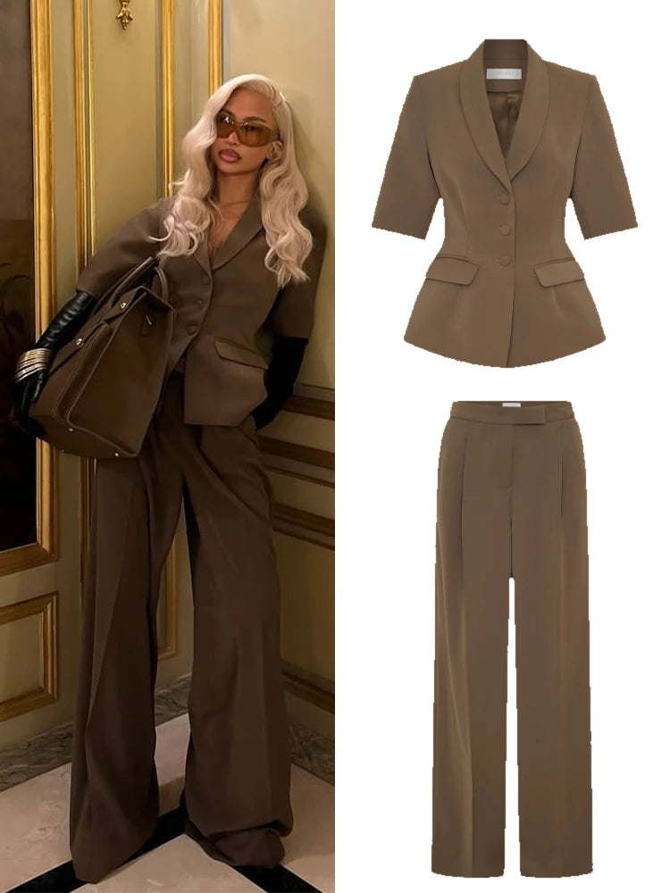 Woman in a brown suit standing next to a matching suit set.