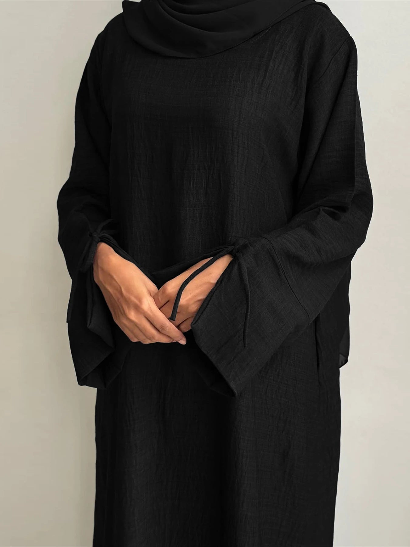 Person wearing a black outfit against a plain background