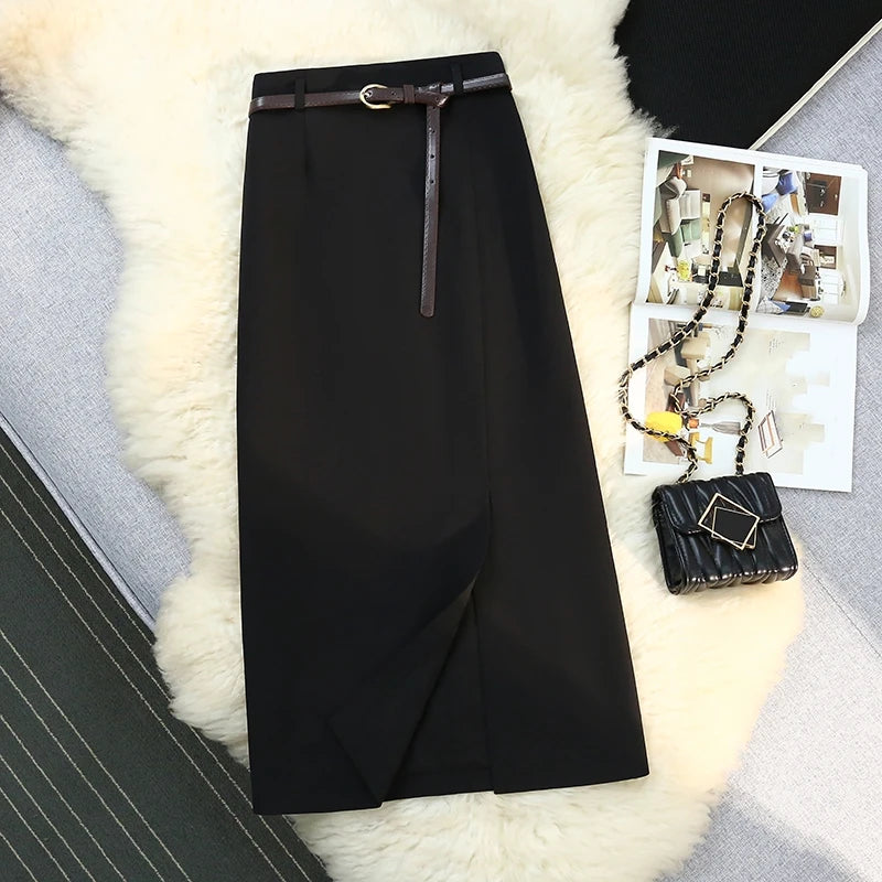 Black skirt with a belt on a textured surface next to a black handbag and photos.