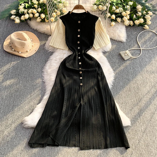 Black pleated dress on a hanger with a white fur rug and floral decorations.