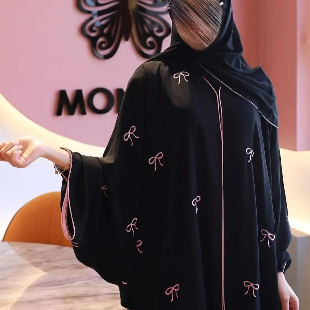 Person wearing a black hoodie with bow patterns in an indoor setting