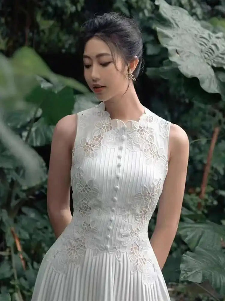 Woman in a white lace dress standing in front of green foliage