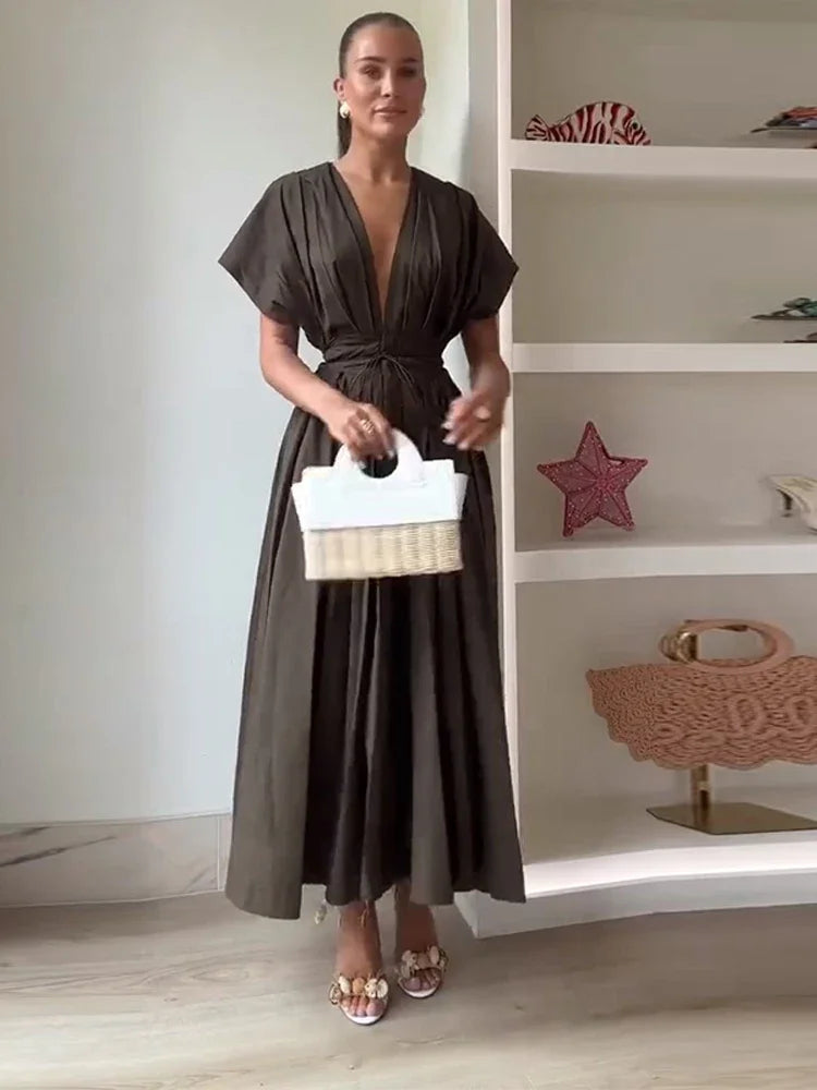 Woman in a brown dress holding a white basket in front of a shelf with bags.