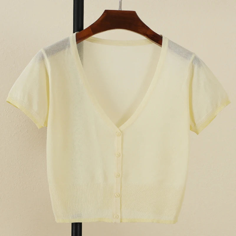 Light yellow cardigan on a hanger against a beige background