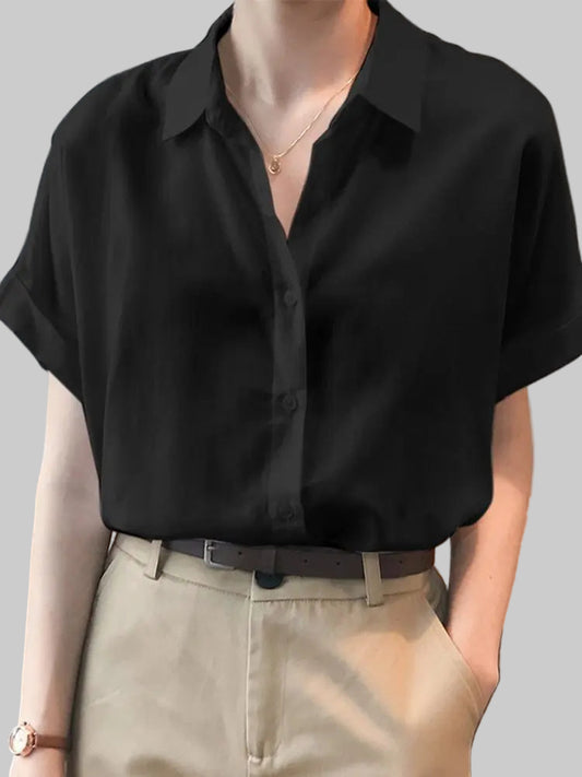 Person wearing a black short-sleeve shirt and beige pants with a blurred background
