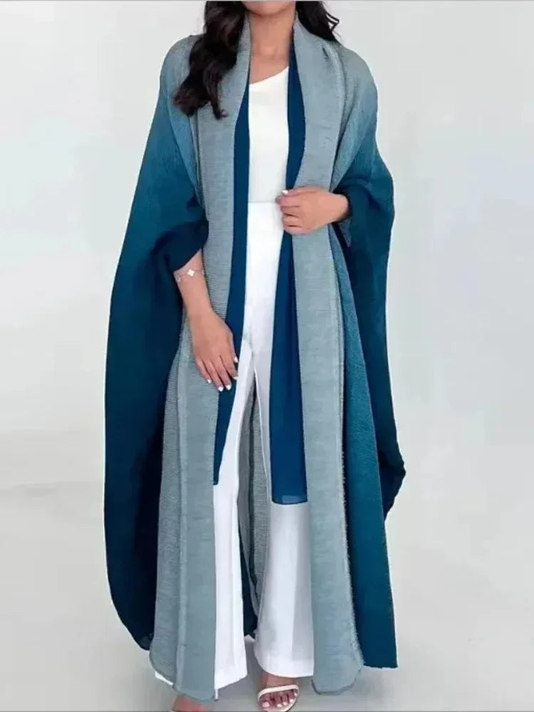 Woman wearing a long, light blue and gray cardigan over a white outfit on a white background