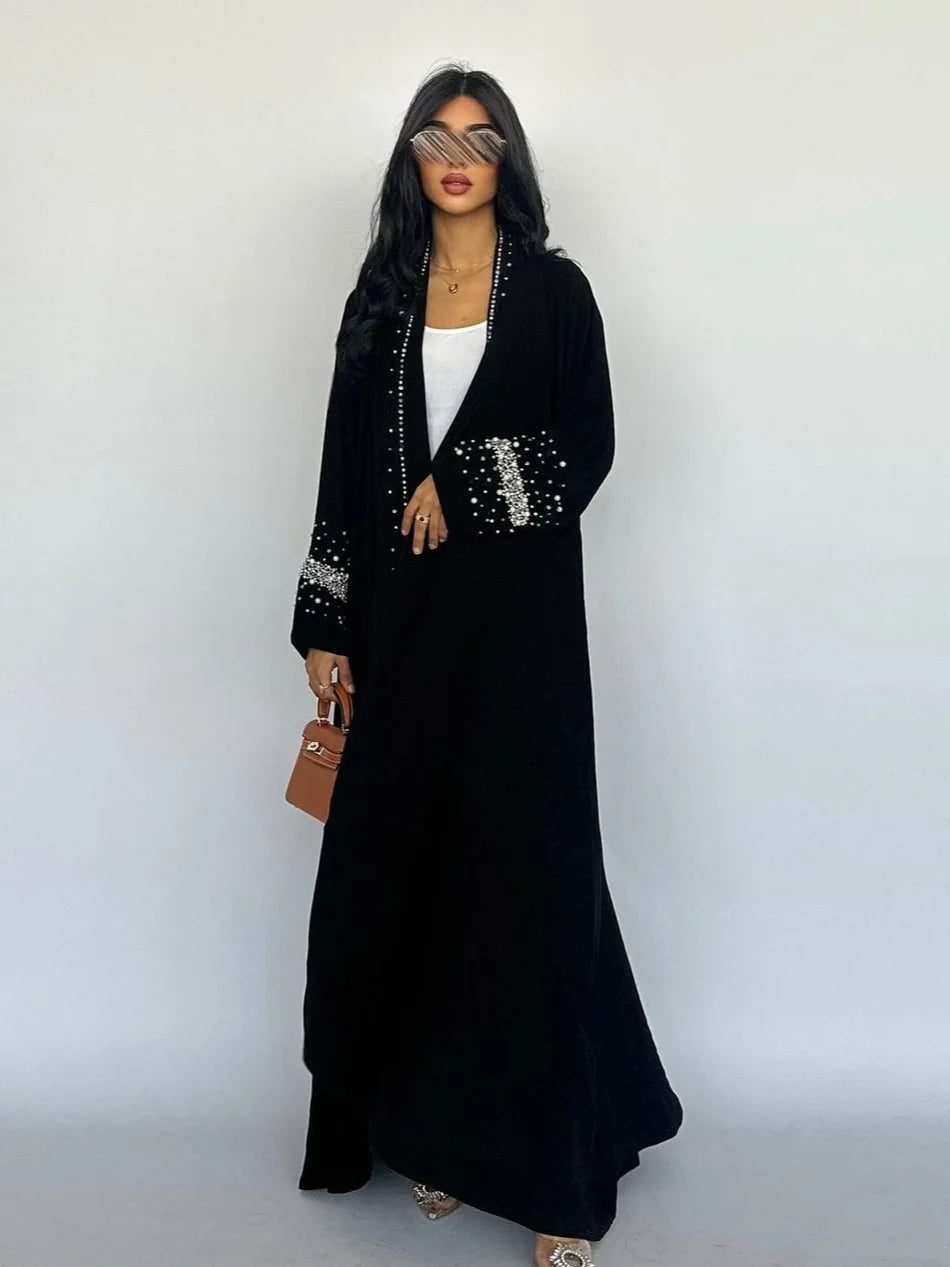 Woman wearing a black dress with silver embellishments against a white background
