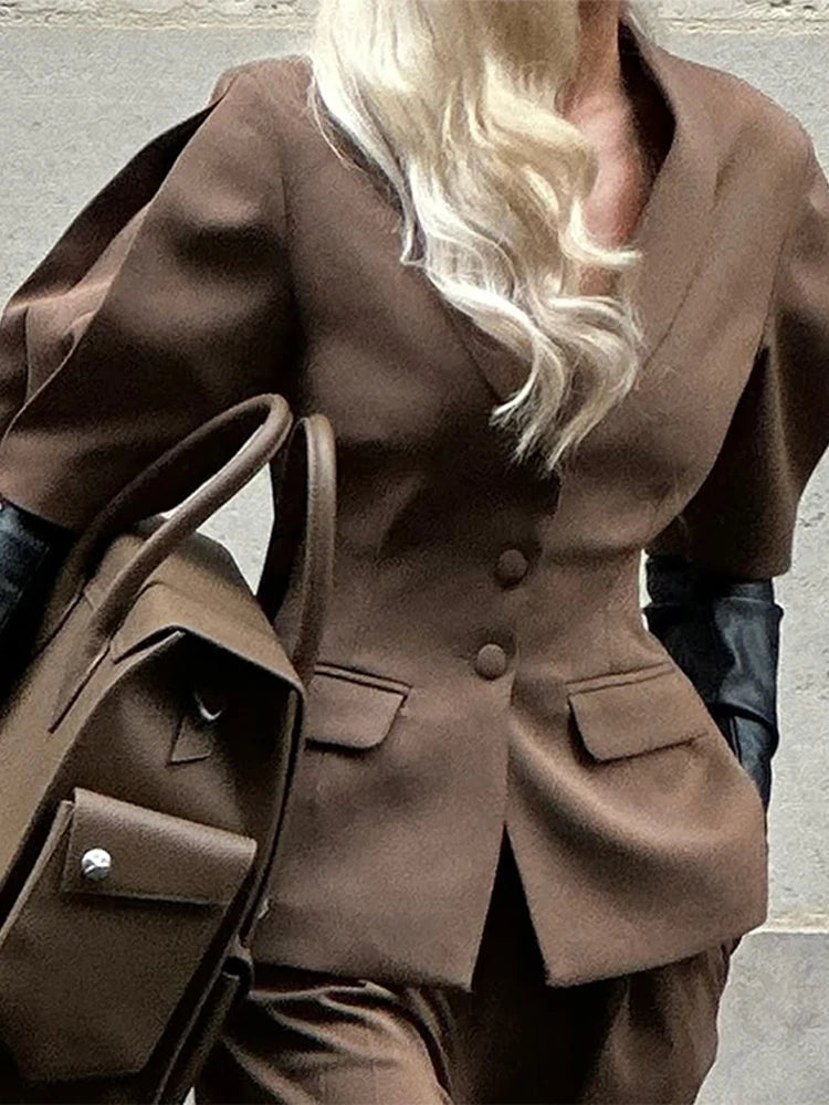 Brown coat with a person wearing it, standing against a neutral background