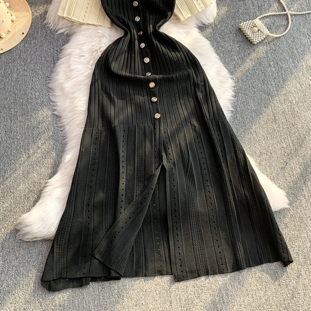 Black pleated dress with buttons on a textured surface