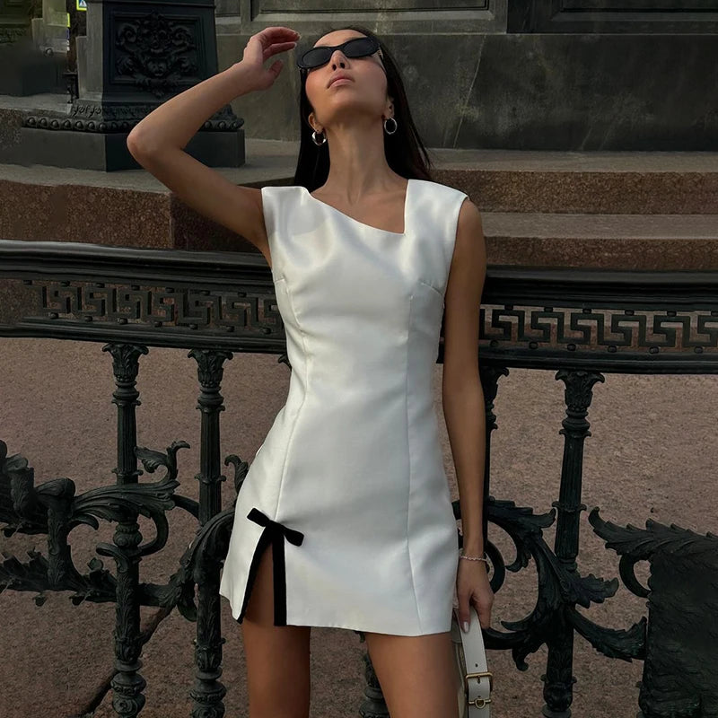 Woman in a white dress standing on stone steps with a decorative railing.